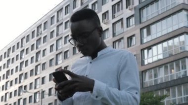 Kapalı kapılar ardında gülümseyen mutlu siyah adam dışarıda cep telefonuyla konuşuyor, gülüyor. Neşeli Afro-Amerikan iş adamlarının telefon görüşmesi, açık havada iş konuşmaları.