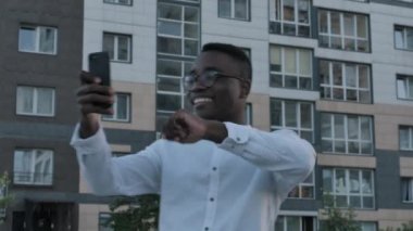 Tablet telefonunda konuşan yakışıklı, mutlu, genç, siyah bir adam. Kameraya el sallayan Afrikalı iş adamının portresi. Cihazda görüntülü sohbet ederken, sohbet ederken.