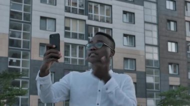 Tablet telefonunda konuşan yakışıklı, mutlu, genç, siyah bir adam. Afrikalı iş adamının portresi kameraya açıklarken cihaz üzerinde görüntülü sohbet ederken, iş konuşmaları yaparken