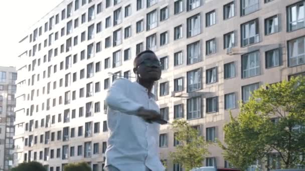 Handsome young african american businessman doing victory dance about successful achievement, black male listening to music and dancing actively alone outdoors near office building — Stock Video