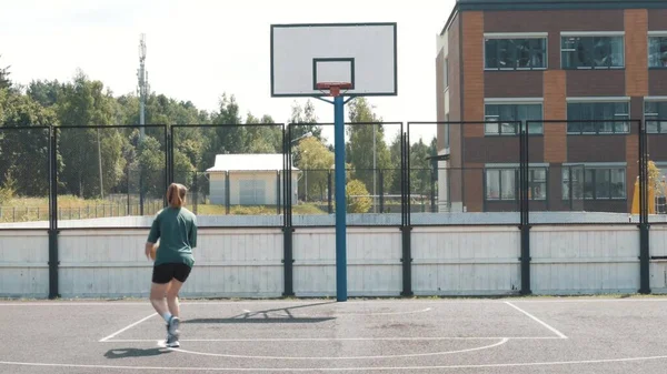 Nahaufnahme einer professionellen Basketballspielerin, die während eines Basketballspiels im Flutlicht-Basketballfeld einen Slam-Dunk macht. Der Spieler trägt Sportkleidung ohne Markenzeichen — Stockfoto