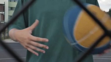 Açık havada sahada egzersiz yapan, basketbol maçından önce antrenman yapan, spor yapan, topla kol kaslarını esneten genç bayan basketbolcu.