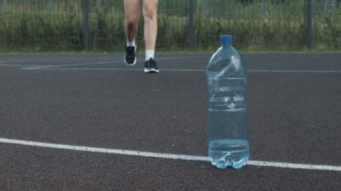 Terli yorgun bayan basketbolcu plastik şişeden taze soğuk su alıyor ve spor müsabakası sırasında yorgun genç kız içiyor.