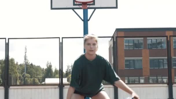Portrét vážná atraktivní ženy basketbalista v uniformě házet, žonglování basketbal mezi rukama na vnitřním hřišti, vyjadřující důvěru, soustředění a odhodlání — Stock video