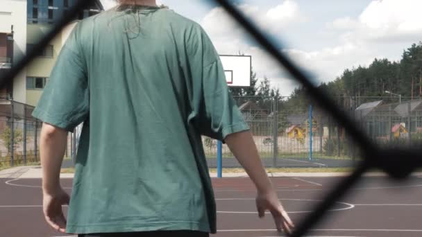 Bakåtbilder av en ung lång kvinnlig basketspelare som tränar och tränar utomhus på den lokala planen. ung kvinna i vita golfstrumpor träning ensam kors studsande med basket — Stockvideo