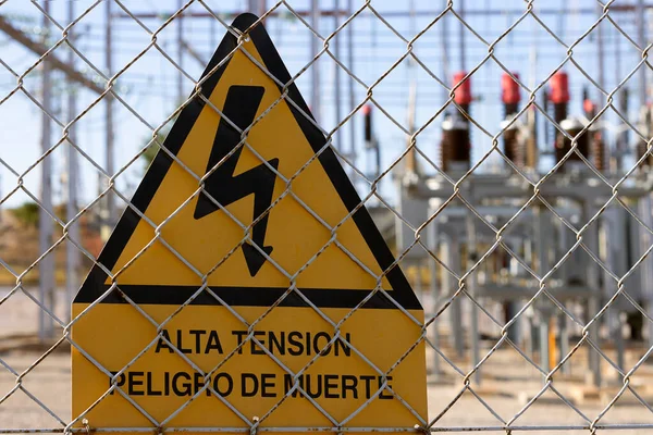 Yüksek voltajlı sarı tabela, İspanyol yüksek voltajlı ölüm tehlikesini gösteriyor, arkanızda çözünmüş bir elektrik istasyonu görebilirsiniz.
