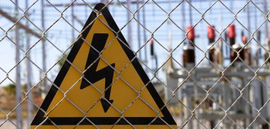 Yüksek voltajlı sarı tabela, ölüm tehlikesi, arkanızda dağınık bir elektrik istasyonu görebilirsiniz.