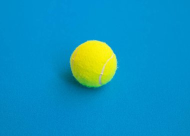 Tek sarı tenis topu mavi arkaplanda izole edilmiş..