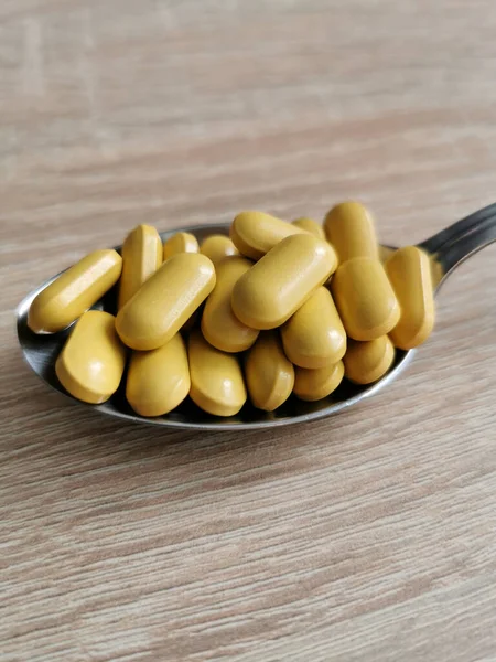 Löffel Mit Gelben Pillen Nahrungsergänzungsmittel Auf Holztisch — Stockfoto