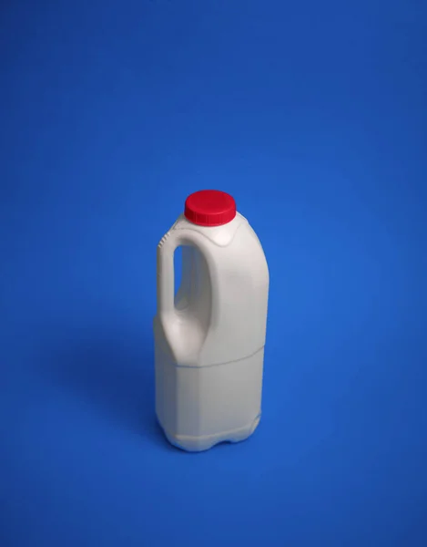 Airtight one gallon milk jug with a red cap on a blue background