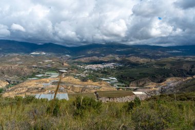 Dağlarla çevrili bir kasaba, bir yol var ve nehri geçen bir köprü var, dağın yamacında birkaç kasaba var.