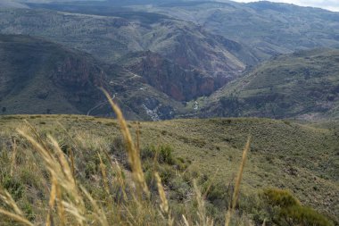 Dağlar ve kaya geçitleri arasından geçen bir nehir, bitki örtüsüyle kaplı dağlık bir arazi.