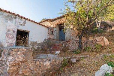 Terk edilmiş çiftlik evi, ön cephesi beyaz ve pencereleri ve kapıları var.