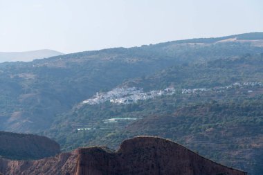 İspanya 'nın güneyindeki dağlık bölgede ağaçlarla çevrili bir kasaba var, gökyüzü açık.