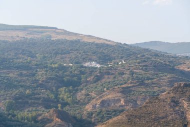 İspanya 'nın güneyindeki dağlık bölgede ağaçlarla çevrili bir kasaba var, gökyüzü açık.