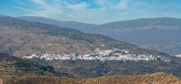 İspanya 'nın güneyindeki dağlık bölgede ağaçlarla çevrili bir kasaba var. Gökyüzü bulutlarla dolu.