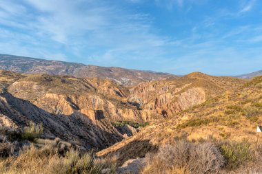 İspanya 'nın güneyindeki dağlık bölgede dağlar bitki örtüsüyle kaplı ve gökyüzü bulutlarla mavidir.