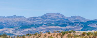 İspanya 'nın güneyindeki dağlık arazi, dağ bitki ve ağaçlarla kaplı, gökyüzü bulutsuz mavidir.