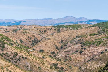 İspanya 'nın güneyindeki dağlık arazi, dağ bitki ve ağaçlarla kaplı, gökyüzü bulutsuz mavidir.