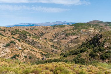 İspanya 'nın güneyindeki dağlık arazi, dağ bitki ve ağaçlarla kaplı, gökyüzü bulutlarla mavidir.