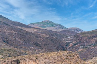 İspanya 'nın güneyindeki dağlık arazi, dağ bitki ve ağaçlarla kaplı, gökyüzü bulutlarla mavidir.