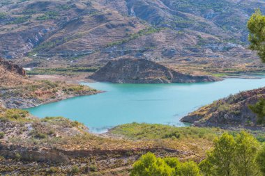 Beninar rezervuarı dağlarla çevrili, su mavi ve dağlar bitki örtüsüyle kaplı.