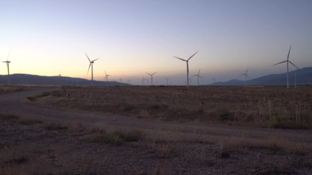 风力涡轮机在黎明时分移动 有高山 天空晴朗 — 图库视频影像