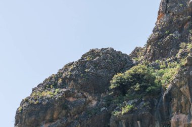 Güney İspanya 'nın dağlık arazisi, dağ bitki örtüsüyle kaplı ve büyük kayaları var, ağaçlar var ve gökyüzü açık.