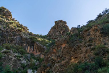 Güney İspanya 'nın dağlık arazisi, dağ bitki örtüsüyle kaplı ve büyük kayaları var, ağaçlar var ve gökyüzü açık.