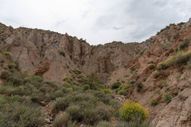Güney İspanya 'nın dağlık arazisi, dağlar aşırı derecede aşınmış, yarı çöl bölgesi, taşlar ve çalılar var ve gökyüzü bulutlu.