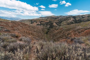 İspanya 'nın güneyinde bitki örtüsüyle dağlık bir arazi, gökyüzü bulutlarla mavidir.
