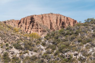 Güney İspanya 'da bol bitki örtüsüyle aşınmış dağ, gökyüzü çok az bulutla berrak.