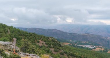 Güney İspanya 'nın dağlarında bulutlar hareket ediyor, dağlarda çalılar ve ağaçlar var.