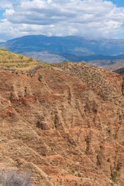 Güney İspanya 'da aşınmış dağ manzarası, çalılık bitki örtüsü, gökyüzü bulutlu