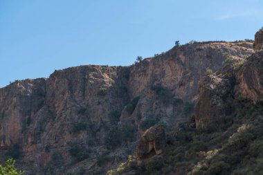 İspanya 'nın güneyindeki dağlık arazide, yamaçta çalılar var ve gökyüzü açık.