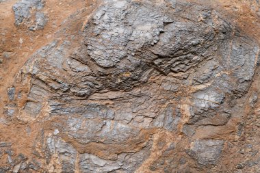 Koyu renk kaya arka planı ve dokusu büyük kayaya gömülü küçük taşlar var.