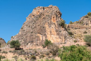 Güney İspanya 'nın dağlık arazisi, yamaçta çalılar var, ağaçlar var ve gökyüzü açık.