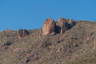 Güney İspanya 'nın dağlık arazisi, yamaçta çalılar var ve gökyüzü açık.