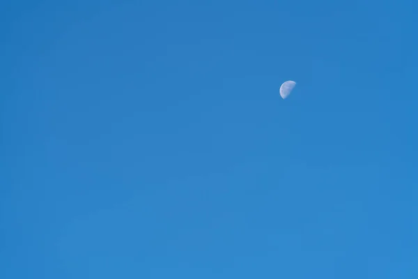 clear sky and the moon in the last quarter, the sky is intense blue and without clouds