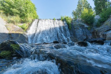 İspanya 'nın güneyindeki bir nehirde şelale, kavak ve çalılar var, gökyüzü açık.