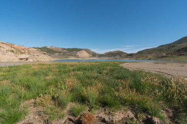 Nehrin ağzındaki bitki örtüsü Beninar rezervuarına kadar uzanır. Bitkilerle kaplı dağlar vardır ve gökyüzü açıktır.