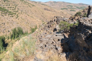 İspanya 'nın güneyindeki Sierra de los Filabres' in dağlık arazisi, çalılar, kuru çimler, çam ormanları, dağ yamacında antik bir köyün kalıntıları var.