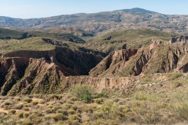 İspanya 'nın güneyindeki dağlık arazi, dağlar çalılık ve ağaçlardan oluşan bitki örtüsüyle kaplı, çok fazla aşınmış alanlar var, gökyüzünde bulutlar var.