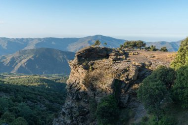 İspanya 'nın güneyinde dağlık bir manzara, bir kaya duvarı var, bir orman var meşe ve çam ağaçları, çalılar var ve gökyüzü açık