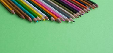 Yeşil arka planda izole edilmiş farklı renklerin çok kullanılan kalemler