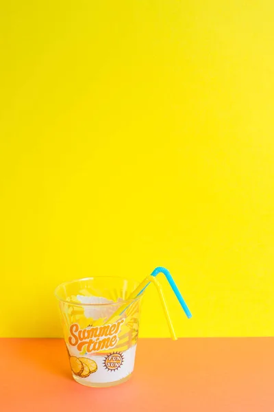 A glass of refreshing drink and straw on yellow and orange background. With stamped summertime and fun in the sun. Different views