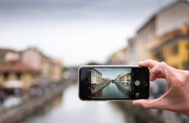 Milano, İtalya - 19 Nisan 2019: İtalya'nın Milano kentinde naviglio kanalının cep telefonuyla fotoğrafını çeken turist. Seyahat konsepti