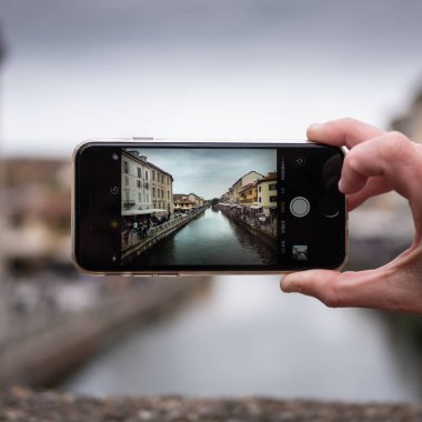 Milan, Italy - April 19, 2019: Tourist taking photo of Naviglio canal in Milan Italy with a mobile phone. Travel concept clipart