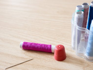 Ağaç zemin üzerinde, sığ alan derinliğinde iplik, makas, makas ve dikiş aksesuarları..