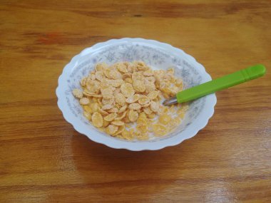 Tahta masada yeşil kaşık ve sütlü tahıl kasesiyle kahvaltı.